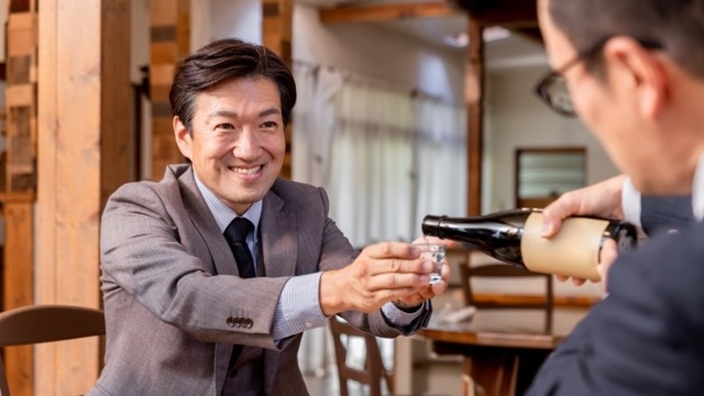 接待中、お酒を注いでもらう男性