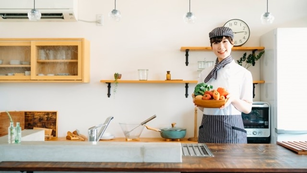 キッチンの前に立つ笑顔の女性調理師