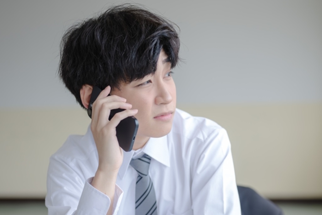 塾講師のアルバイトを辞めることを電話で申し出ようとする男子大学生