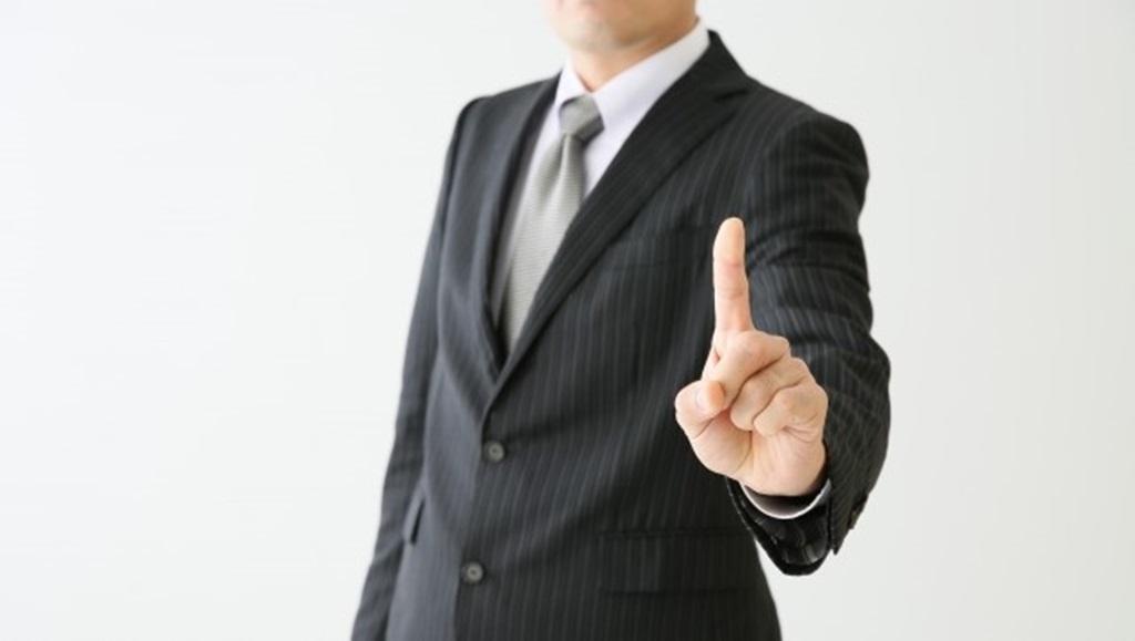 スーツを着た男性が人差し指でのジェスチャー(大事なポイントを強調)