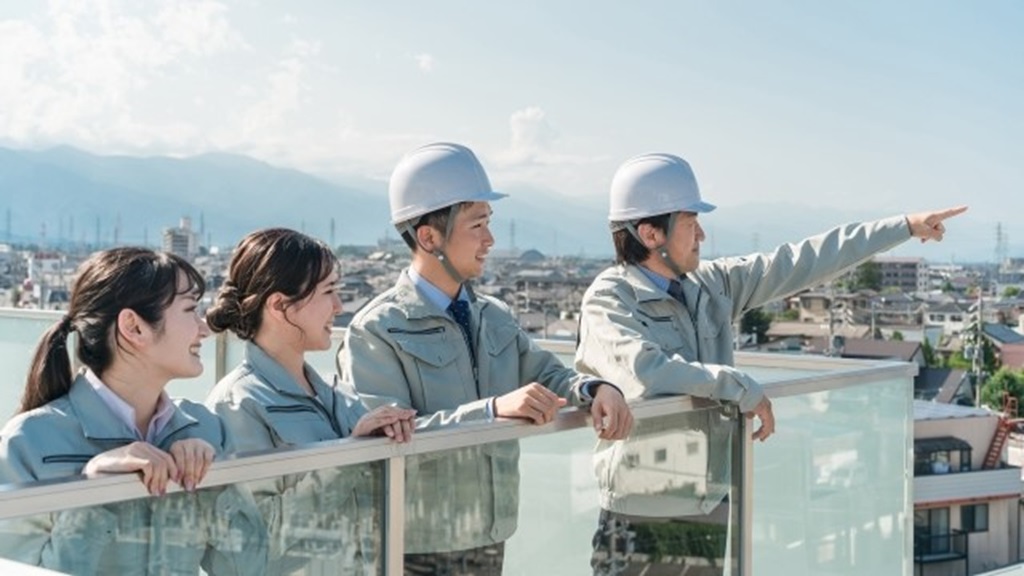 遠くの空を指さす作業員4名