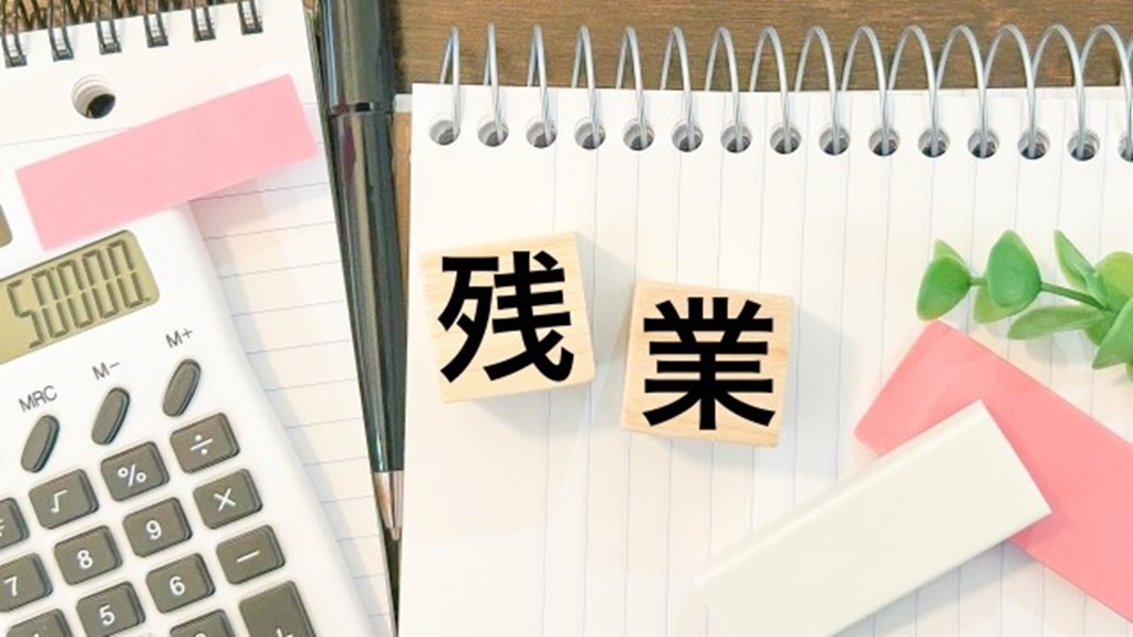 積み木に書かれた残業の文字と電卓