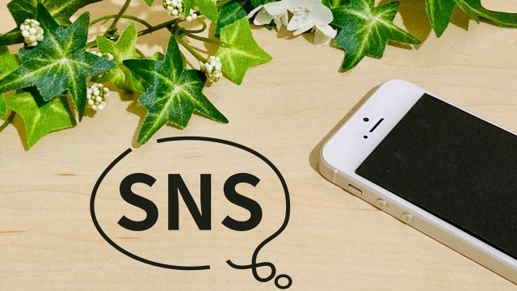 机の上に書かれたSNSの文字と置かれたスマホ