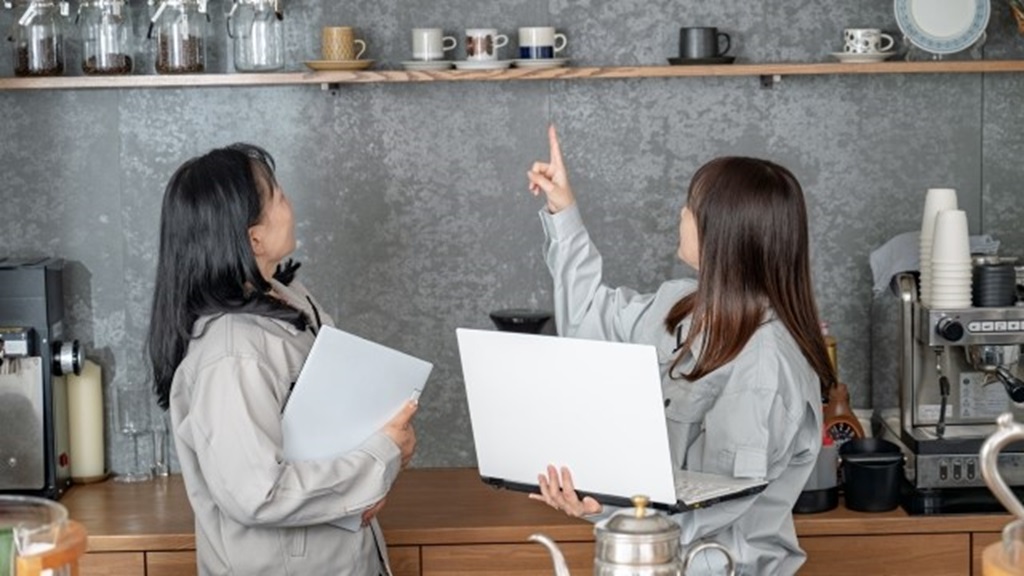 作業福を着た女性2名が店の内装について話している様子