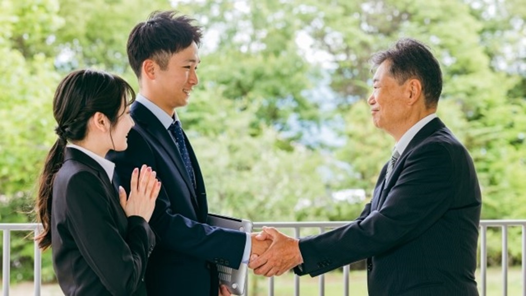 若手社員と握手するベテラン社員