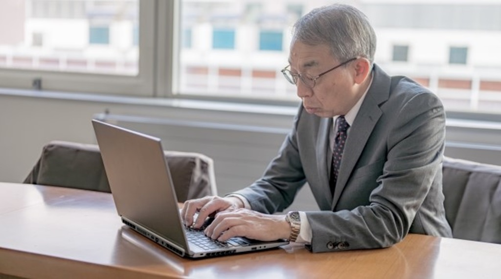 慣れないパソコンで作業するシニア人材