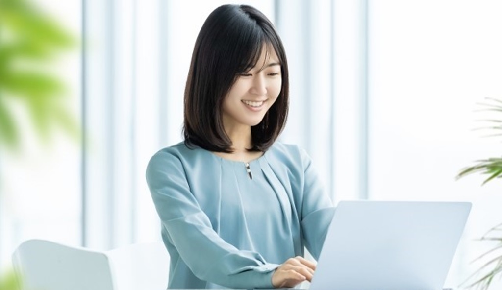 ノートパソコンを使っている笑顔の女性