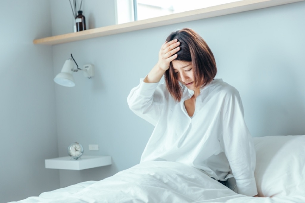 朝起きて頭痛に悩む女性