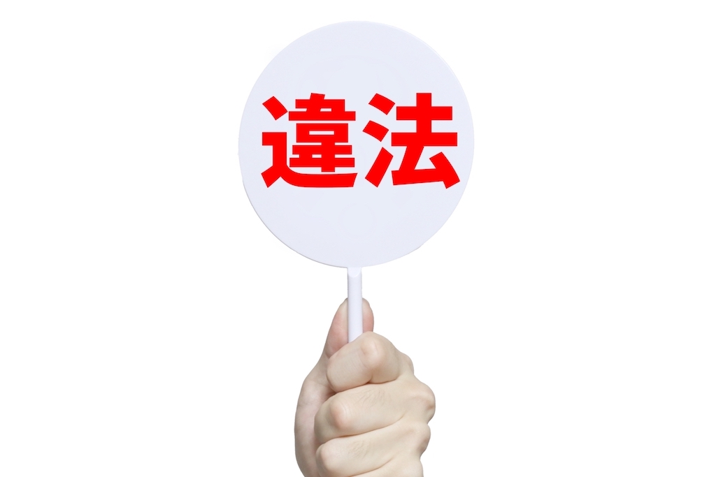 違法と書かれたプラカード