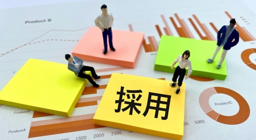 グラフが載った紙に置かれる採用と書かれた付箋と採用担当者をイメージした人形
