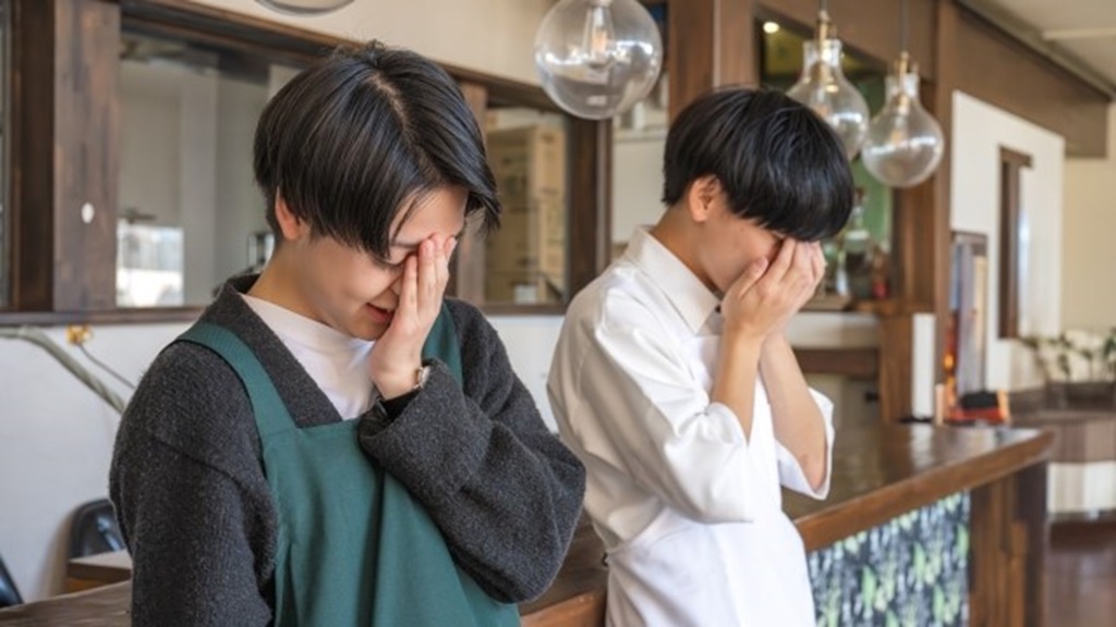 従業員の離職に顔を覆って残念がる2名の男性