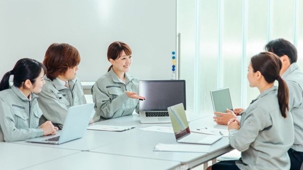 パソコンの画面を周りに見せて説明する中小企業の従業員