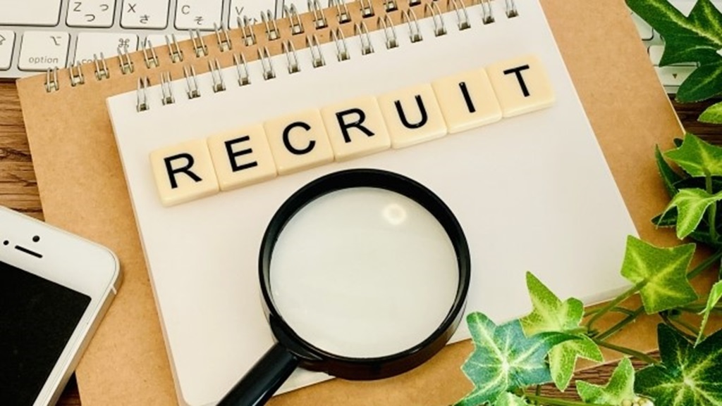 RECRUITと書かれたベージュの板と虫眼鏡