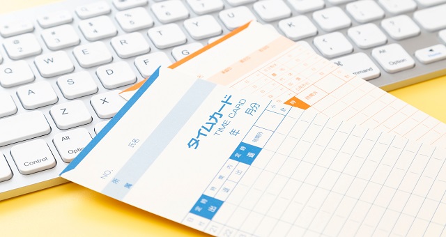 パソコンのキーボードに重なるタイムカード