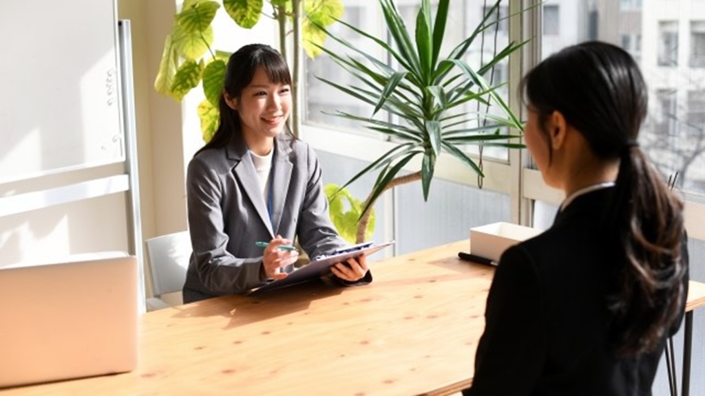 面接担当者の女性と応募者の女性が日当たりのよい場所で面接を行う様子